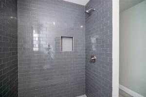 y baño con ducha de azulejos grises. en Tranquility @ Downtown FortWorth en Fort Worth
