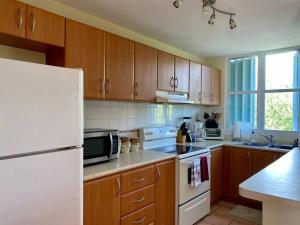 Una cocina con gabinetes de madera y un refrigerador blanco. en Villas Del Mar Beach Resort, en Loiza