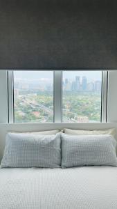 a bed with a large window with a view of a city at San Lorenzo Place in Manila