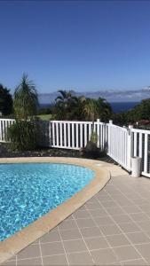 une piscine en face d'une clôture blanche dans l'établissement L'Eskalya *** avec jacuzzi et piscine partagée, vue océan, à Saint-Joseph