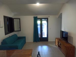 ein Wohnzimmer mit einem blauen Sofa und einem TV in der Unterkunft Case Lénora in Saint-Joseph