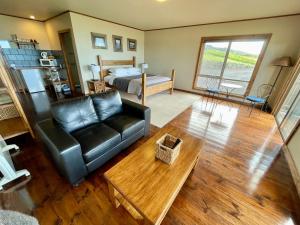 a living room with a leather couch and a bed at Castaways Apollo Bay in Apollo Bay