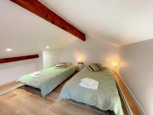 two beds in a attic bedroom with two lamps at Cosy Gîte à Azay-le-Rideau avec Wifi, Clim, tout inclus, idéal pour 2 adultes et 2 enfants, proche châteaux - FR-1-381-567 in Azay-le-Rideau