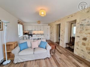 ein Wohnzimmer mit einem Sofa und einer Küche in der Unterkunft Gîte Theuville, 3 pièces, 4 personnes - FR-1-649-28 