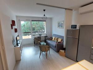 ein Wohnzimmer mit Couch und Kühlschrank in der Unterkunft T2 climatisé 3* avec Loggia, Parking sécurisé, WiFi, proche plage - Bormes-les-Mimosas - FR-1-610-98 in Bormes-les-Mimosas