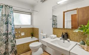 a bathroom with a sink and a toilet and a tub at Tsapas Homes in Doncaster East