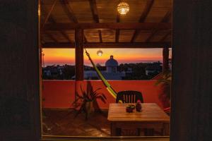 a table and a chair on a balcony with a sunset at Cielito Lindo Suites in Puerto Escondido