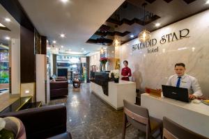 a man sitting at a counter with a laptop in a restaurant at Splendid Holiday Hotel Spa in Hanoi +50 photos