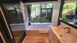 a bathroom with a tub and a sink and two windows at Dewdrop Cottage in Hastings +21 photos