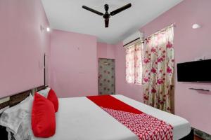 Schlafzimmer mit einem Bett mit roten Kissen und einem Deckenventilator in der Unterkunft H R Palace in Dīgha
