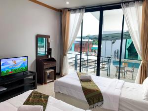 a bedroom with two beds and a television and a balcony at Three Bridges Hotel in Nan
