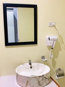 uma casa de banho com um lavatório branco e um espelho. em Three Bridges Hotel em Nan