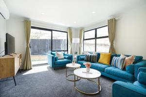 a living room with blue couches and a tv at Charming 4bds House with 3 bathrooms Brand New in Hamilton