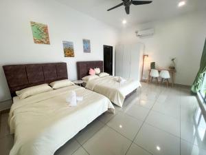 deux lits dans une chambre aux murs blancs dans l'établissement Desaru 20Pax Cozy Chill villa Private Pool, à Johor Bahru