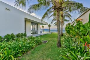 een huis aan het strand met een palmboom bij Dreamy Beach Villas And Resort in Da Nang