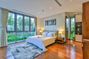 a bedroom with a large bed and large windows at Dreamy Beach Villas And Resort in Da Nang