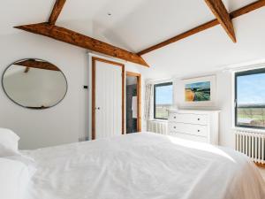 a bedroom with a white bed and a mirror at The Hollow At The Linhay in Sawtry