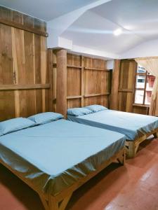 two beds in a room with wooden walls at Chadatarn HomeStay in Ban Pok Nai