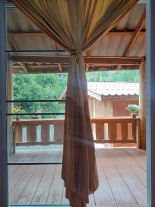 an open glass door with a curtain on a porch at Chadatarn HomeStay in Ban Pok Nai