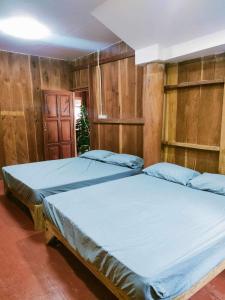 a bedroom with two beds and wooden walls at Chadatarn HomeStay in Ban Pok Nai