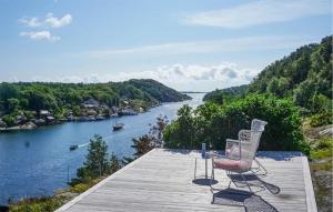 a couple of chairs sitting on a dock next to a river at Lovely Home In Helgeroa With Harbor View in Helgeroa