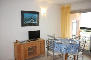 ein Esszimmer mit einem Tisch mit Stühlen und einem Fernseher in der Unterkunft Appartement vue mer. A 40m de la plage. in Pornic