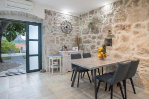 a kitchen with a table and chairs and a stone wall at Villa Ana in Zaostrog
