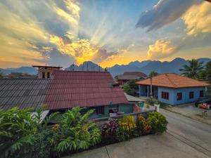 萬榮的住宿－Saphaothong guesthouse，享有房子的景色,背景是日落