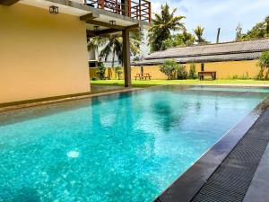 a swimming pool in front of a house with blue water at Bungalow By Tropical Villa in Weligama