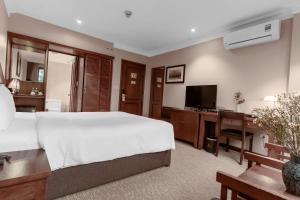 Dormitorio con cama, escritorio y TV en La Passion Classic Hotel, en Hanói