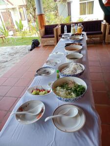 a long table filled with plates and bowls of food at LA PETITE MANGROVE Resort in Phumĭ Srângam
