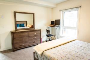 a bedroom with a bed and a dresser and a mirror at Suite Lines Revy - One Bedroom Near RMR in Revelstoke