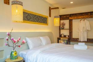 a bedroom with a white bed and a vase with flowers at Mimosa Homestay in Hanoi
