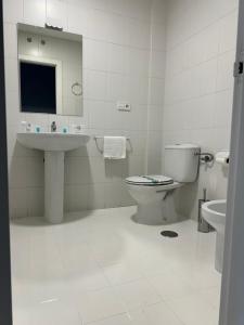 a white bathroom with a toilet and a sink at Hotel Vanity in Zamora