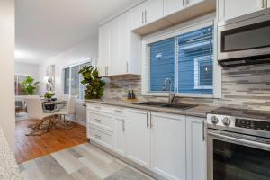 uma cozinha com armários brancos, um lavatório e uma janela em La Maison em Vancouver