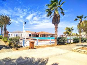 a house with a white fence and palm trees at Feeling Cabo Verde in Beirona