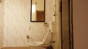 La salle de bains est pourvue de toilettes blanches et d'un miroir. dans l'établissement NIRMAN HOMESTAY 5 minutes walk to beach, à Purî