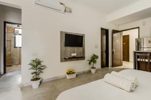 a white bedroom with a bed and a tv on the wall at Lime Tree Hotel - Golf Course Road, Sector-43, Gurugram in Gurgaon