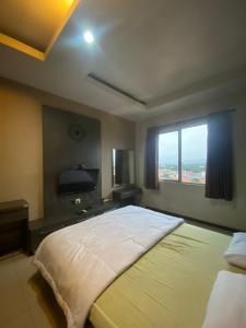 ein großes Bett in einem Schlafzimmer mit Fenster in der Unterkunft Apartement Studio The Edge Baros by Sky in Cimindi