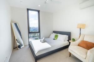 a bedroom with a bed and a couch and a chair at Central Location! Boutique 2BR Apartment with Pool & BBQ near South Bank and City in Brisbane