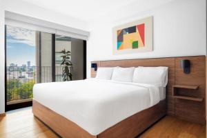 a bedroom with a large bed and a large window at Lumina at Taman Condesa in Mexico City