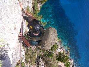 a man is standing on a rock near the water at Hotel Bia Maore in Baunei