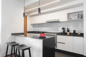 Una cocina con gabinetes blancos y encimeras negras. en Lumina at Taman Condesa, en Ciudad de México