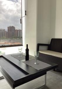 una mesa con una botella de vino y dos copas en APARTAMENTO CON TERRAZA CERCA DEL AEROPUERTO, en Guatemala