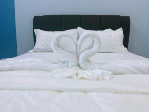 uma cama branca com dois cisnes feitos de toalhas em Good Night BD Motel 
