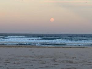 a moon rising over a beach with the ocean at The White Cottage Byron Bay in Suffolk Park