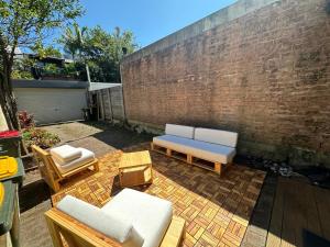 a patio with couches and chairs and a brick wall at Elegant 2 Bedroom home close to city buz Bridge RD 2 E-Bikes Included in Sydney