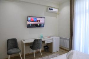 Zimmer mit einem Schreibtisch, 2 Stühlen und einem TV in der Unterkunft STATUS HOTEL in Qarshi
