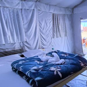Una cama con dos cisnes blancos. en The FnF Resort & Camping - Rishikehs en Rishīkesh