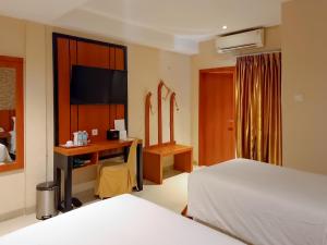 a bedroom with a bed and a desk with a television at Portola Arabia Hotel Banda Aceh in Banda Aceh